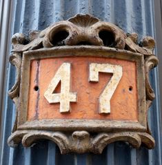 the number 477 is written in white on an old rusted metal wall plaque