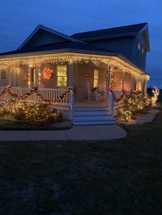 a house covered in christmas lights and wreaths on the front porch, with stairs leading up to it