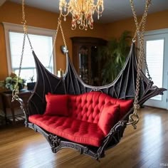 a red couch hanging from a chandelier in a living room with wood floors