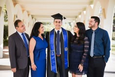 a group of people standing next to each other in graduation gowns and ties smiling at the camera