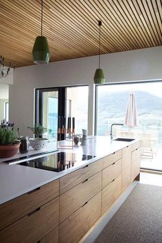 a kitchen with an island counter and two hanging lights over the stove top, next to a sliding glass door that leads out onto a balcony