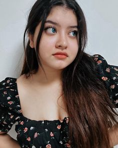 a young woman with long hair posing for the camera while wearing a black floral top