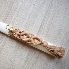 a crocheted rope is tied to the end of a white pipe on a wooden surface