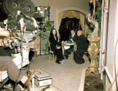 a man and woman sitting at a table in front of a camera on a tripod