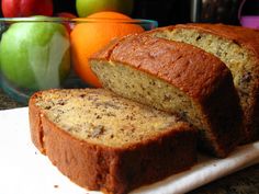 sliced loaf of banana bread next to apples and oranges