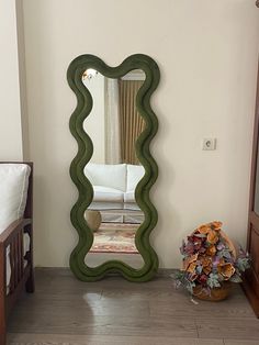 a mirror sitting on top of a wooden floor next to a bed