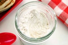 a jar filled with white powder next to a red and white checkered table cloth