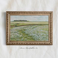 a painting hanging on the wall above a bed of blue and white wildflowers