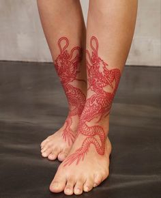 a woman's legs with red tattoos on them