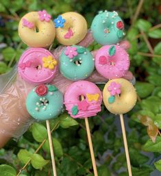 there are many doughnuts on the stick with pink and blue frosting, decorated with flowers