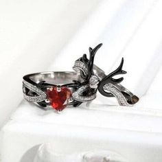 two silver rings with red heart shaped stone in center and antlers on each side