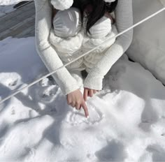 a woman holding a baby in her arms while sitting on the ground covered in snow