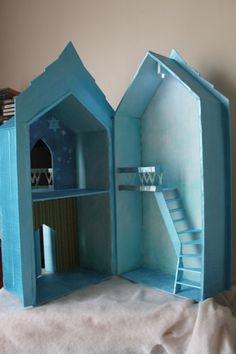 a blue dollhouse with stairs and a staircase inside it on a white sheeted surface