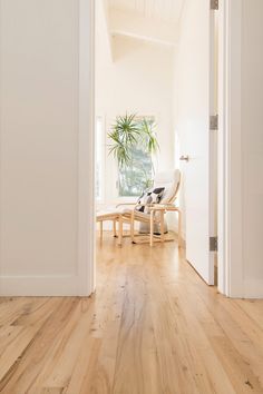 an open door leading to a living room with wooden floors and white walls, along with a chair