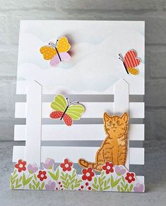 a card with some paper cut outs on it and butterflies flying over the cat in the grass