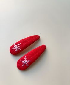 pair of red knitted shoe covers with white snowflakes on them sitting next to each other