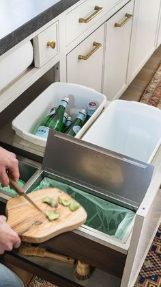 a person cutting food in an open drawer with a wooden chopping board and knife