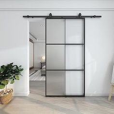 an open sliding door in a white room with a potted plant next to it