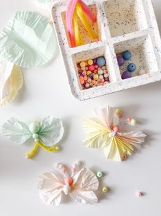 paper flowers and other crafting supplies laid out on a white surface, including tissue pom poms