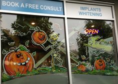 two windows decorated with halloween stickers in front of a storefront window that says, book a free consulti