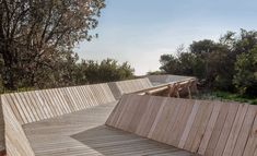 a wooden walkway with benches and trees in the background