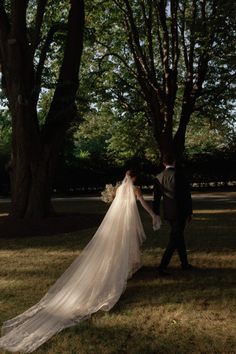 a bride and groom walking through the grass