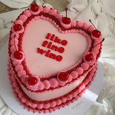 a heart shaped cake with the words like time wine written on it and cherries