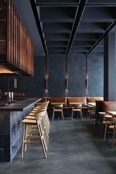 the interior of a restaurant with wooden tables and bar stools, dark walls and concrete flooring