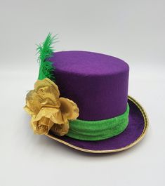 Adult Deluxe Purple Top Hat with Green Feather, band and Gold Rose. Top hat features a velvet finish. Hat measures approximately 58cm or 7 1/4.  Brim is approximately 1.5 inches wide. Great for Mardi Gras, Halloween, Theater, Cosplay and more. *partially handmade, partially machine sewn.* Adjustable Short Brim Top Hat For Carnival, Adjustable Costume Hats For Kentucky Derby Themed Events, Adjustable Short Brim Costume Hat For Carnival, Adjustable Short Brim Carnival Costume Hat, Adjustable Hats For Themed Events At Carnival, Adjustable Hats For Themed Events And Carnival, Mardi Gras Carnival Costume Hat, Mardi Gras Party Costume Hat, Adjustable Hats For Kentucky Derby And Carnival