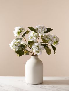 a white vase filled with flowers on top of a table