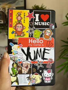 someone holding up a book with many stickers on the front and back cover that says hello, my name is yome