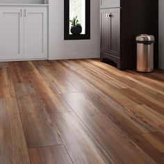 a kitchen with white cabinets and wood floors is shown in this image, there is a trash can on the floor