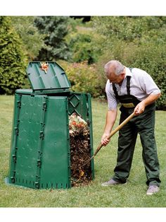 a man with a shovel digging in the ground next to a green trash can and composting bin