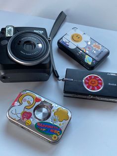 four different types of cameras sitting on a white table with one being a camera and the other is an mp3 player