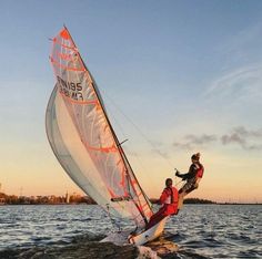 two people on a sailboat in the middle of the ocean at sunset or sunrise