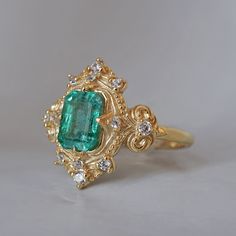 Read about our payment plans before proceeding. Palais d'Émeraude: A Parisian Royal Masterpiece Introducing the Emerald Palais Diamond Ring, an exquisite ring that captures Parisian elegance and sophistication. At its center, a lush emerald evokes the opulence of royal gardens. Inspired by Parisian palaces, this ring features delicate curves and ornate details that wrap around the vibrant emerald. The meticulous craftsmanship makes it a true masterpiece, fit for royalty. "Palais" translates to "Palace," reflecting the regal beauty and timeless charm of this piece. The emerald symbolizes rebirth, love, and fortune, elegantly embraced by the intricate band. All orders come in our Tippy Taste ring box. This ring is handmade and designed in NYC. 14K or 18K solid gold Natural emerald-cut emeral Parisian Elegance, Royal Garden, Jewelry Lookbook, Natural Emerald, Ring Box, Emerald Cut, Fashion Rings, Solid Gold, Diamond Ring