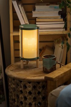 a table with a lamp on top of it next to a coffee cup and bookshelf