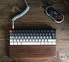 a computer keyboard sitting on top of a wooden table next to a controller and mouse