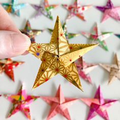 a hand is holding a small origami star in front of many smaller ones