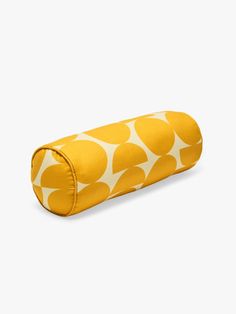 a yellow and white polka dot print roll pillow on a white background with an orange circle pattern