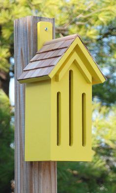 a yellow bird house on top of a wooden post