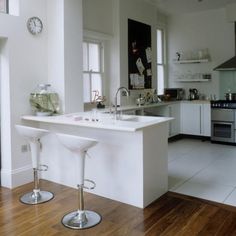 two stools sit in front of a kitchen counter with a clock on the wall