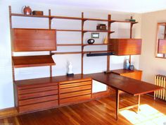 a room with wood floors and shelves on the wall, along with a wooden table