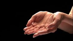 a person holding out their hands in front of the camera on a black background,