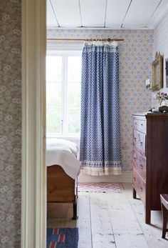 a bedroom with blue and white wallpaper, wooden furniture and a bed in the corner