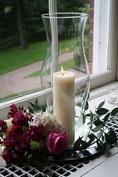 a candle and some flowers on a window sill