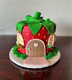 a strawberry shaped cake sitting on top of a wooden table