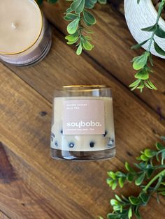 a candle sitting on top of a wooden table next to a potted plant and some candles