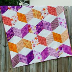 a colorful quilt hanging on a wooden fence