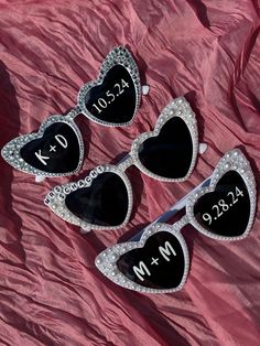 three heart shaped sunglasses with the names and date on them, sitting next to each other